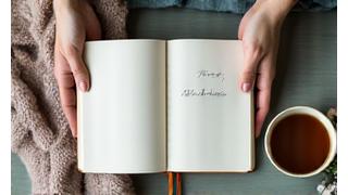 Overhead view of a person journaling next to a warm cup, symbolizing mindful reflective practice and mental clarity.