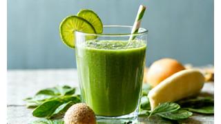 A vibrant green smoothie in a glass, surrounded by fresh ingredients like spinach and avocado, highlighting quick and nutritious meals.