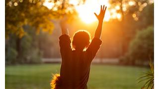A person performing gentle stretches outdoors during sunrise, emphasizing morning exercise and flexibility.
